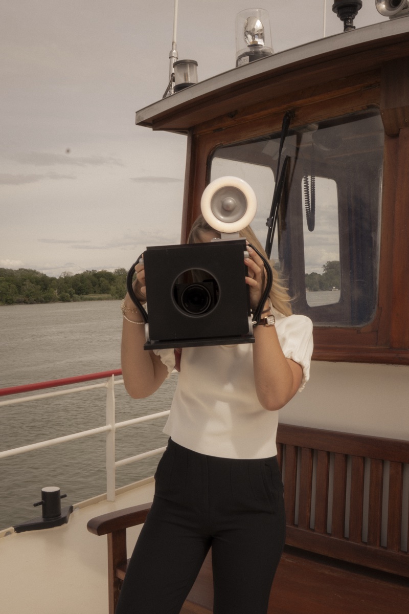 imprinted Zeitungsfotografie – Jasmin Meilner mit Vintage-Kamera bei einem Event auf dem Schiff