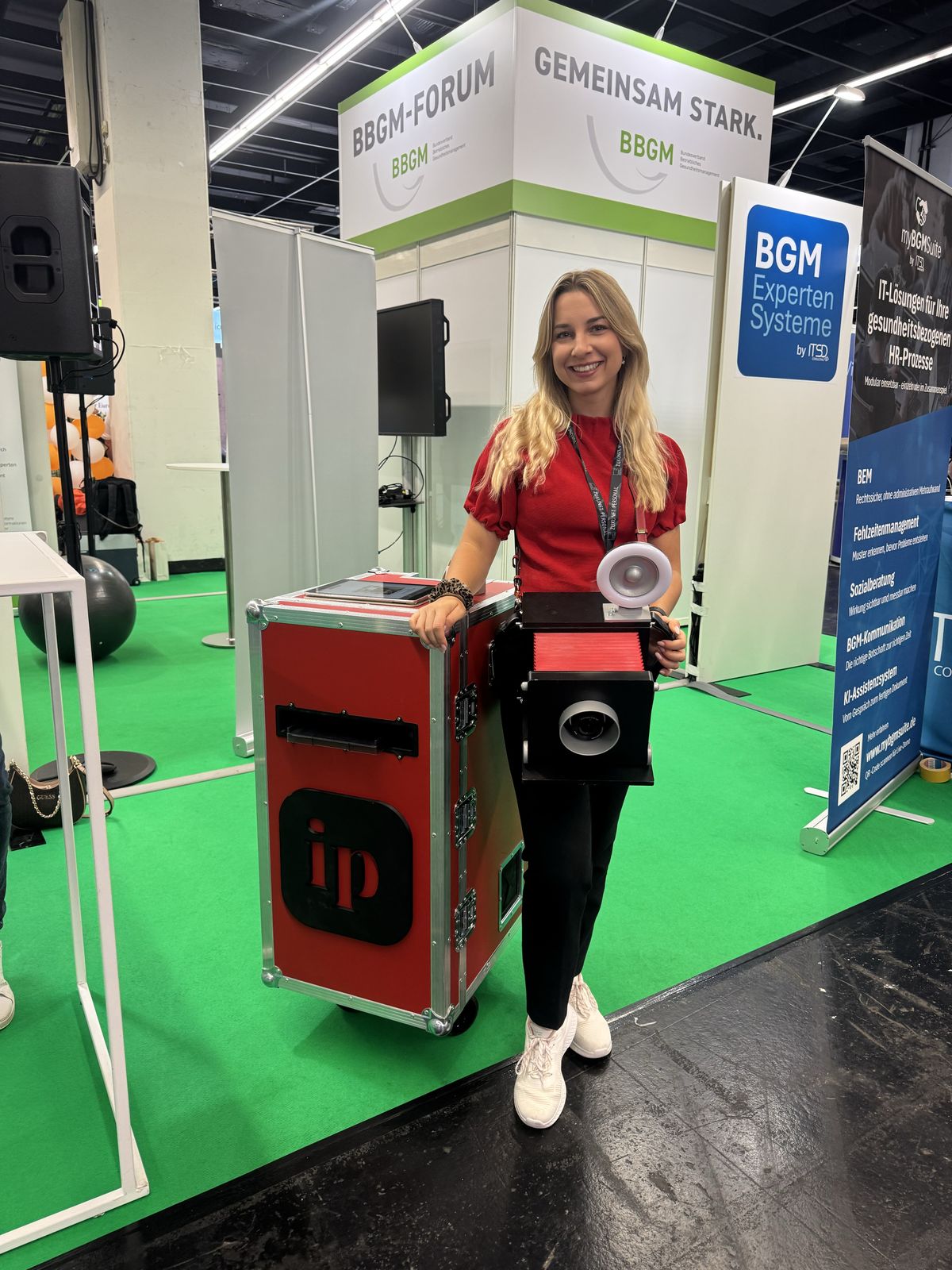 Der rote imprinted Koffer mit Kamera und Drucker an einem Messestand